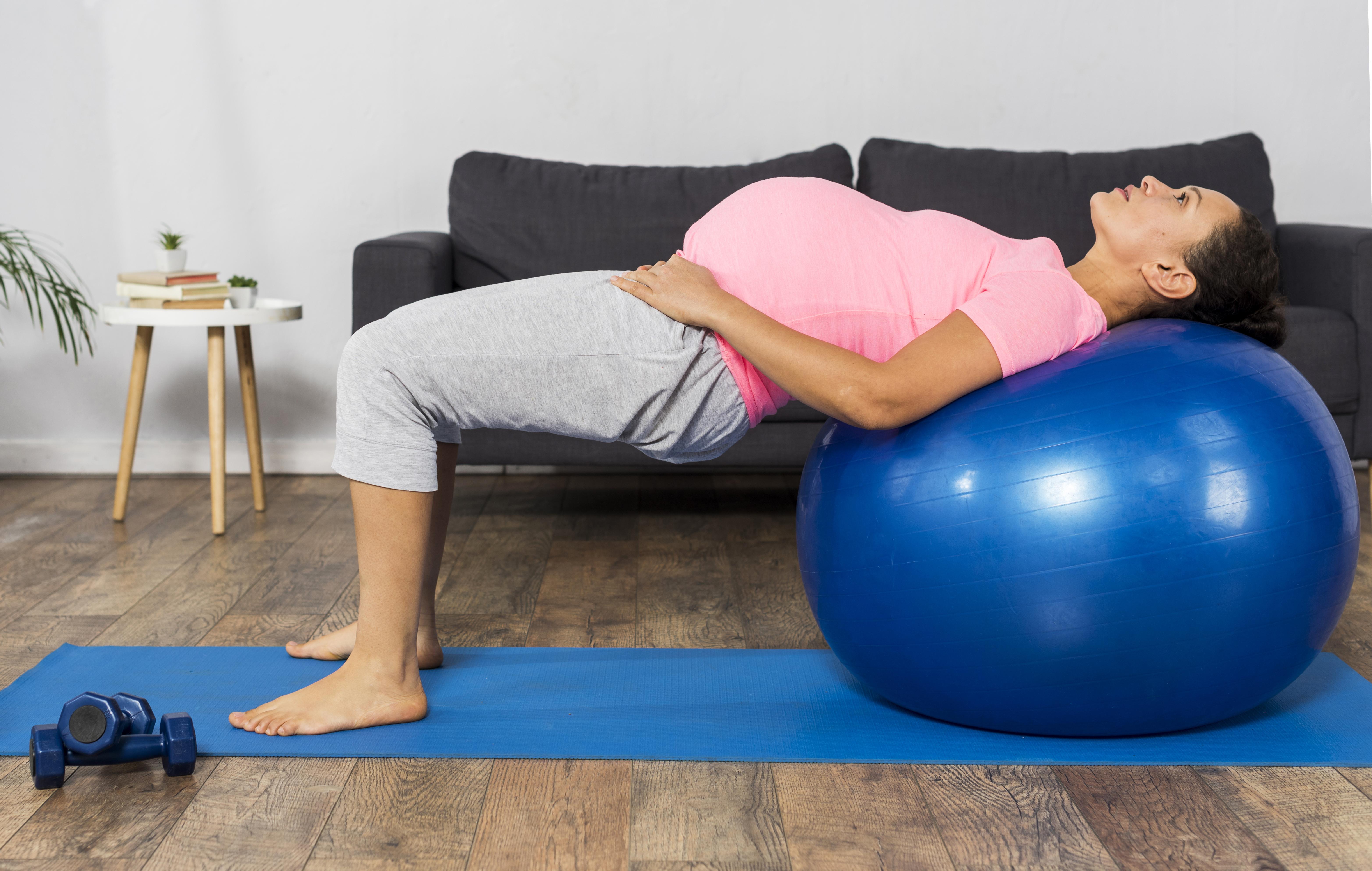 side view pregnant woman using ball exercise home
